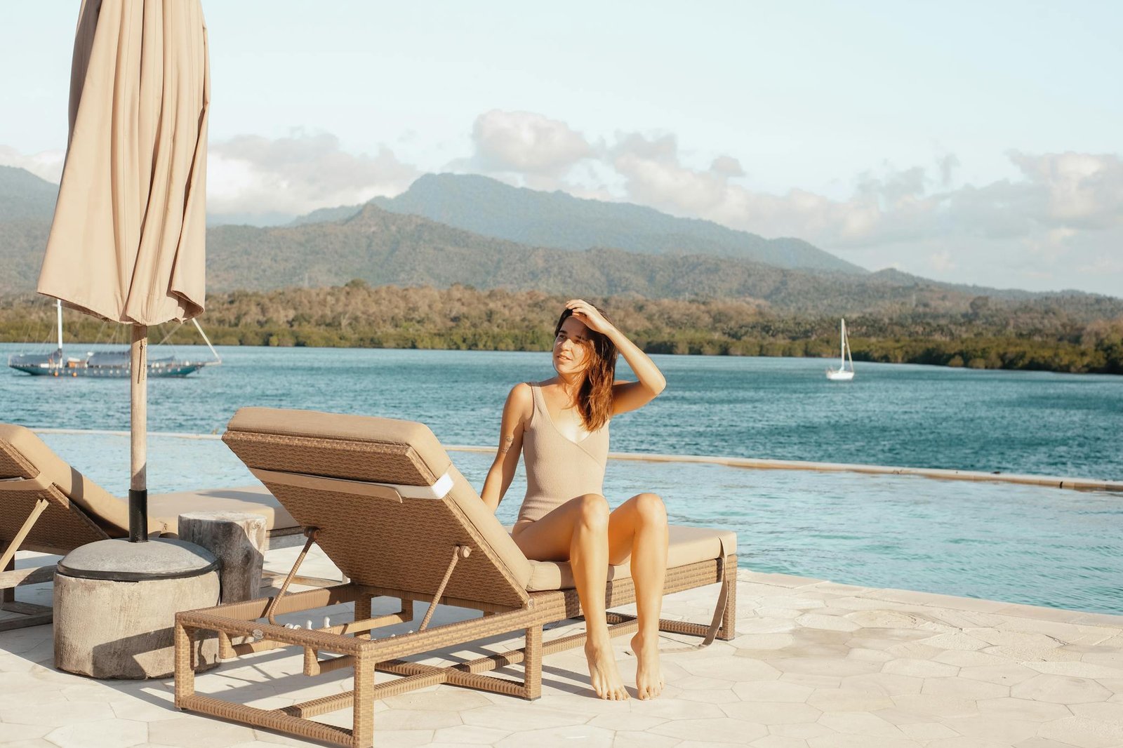 Woman in swimwear sitting by a pool with mountain view. Perfect vacation setting.